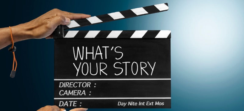 A person holding a filming slate entitled what's your story