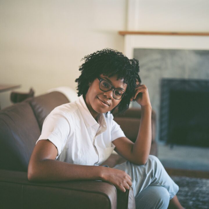 Black woman sitting on couch posing for picture
